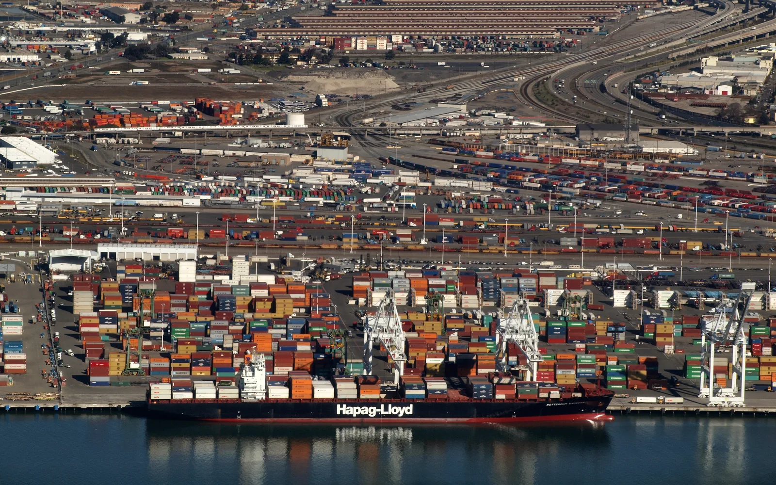 Aerial view of the Port of Oakland showing container ships and cargo loading facilities along the waterfront